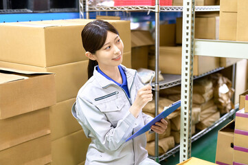 在庫を確認する作業員の女性　工場　倉庫