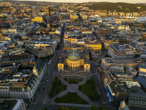 Aerial view of the Norwegian Parliament building, Stortinget, standing proudly amidst the city's architectural tapestry, illuminated by the soft glow of the setting sun, Oslo, Oslo, Norway.