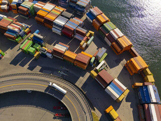 Aerial view of a vibrant array of stacked shipping containers at the port, contrasting with the dark water and the curving road below, Oslo, Norway.