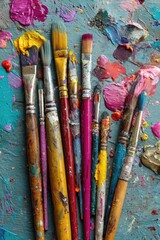 Obraz premium Used paintbrushes, various colors, and splatters of paint on a textured surface
