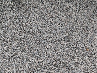 Crushed grey gravel texture spread across a construction site during midday light
