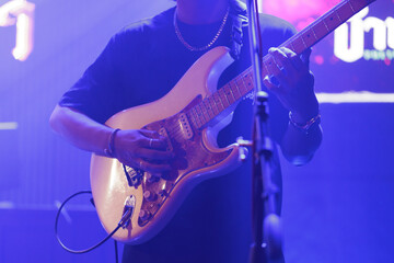 Obraz premium Close-Up of Guitarist Performing Live on Stage under Blue and Purple Lighting