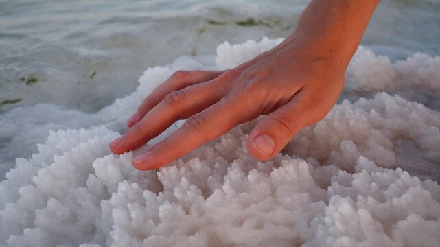 Touching the white salty crystals on the selenium sea with your finger and hand