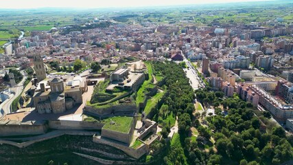 Aerial view of the Gardeny Castle, a Templar fortress, surrounded by green trees and buildings in the urban landscape, Lleida, Spain.