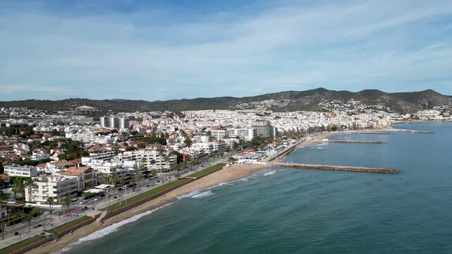 Aerial view of the Spanish coastline with white buildings contrasting against the turquoise sea and sandy beach, Sitges, Barcelona, Spain.