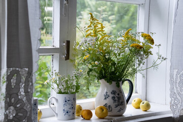 Yellow flowers in the window and apples
