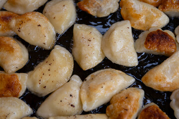 Traditional Polish dumplings frying in pan – homemade dumplings close-up