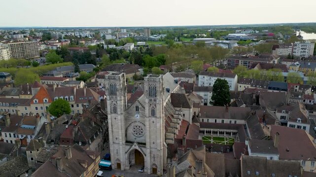 Aerial view of the towering Chalon Cathedral amidst a sea of terracotta rooftops, contrasting against the lush green trees, Chalon-sur-Sa&ocirc;ne, France.