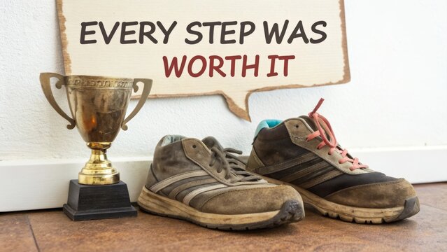 Worn Shoes with Trophy and Motivational Quote on Wall Background