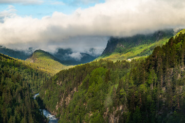 Norway landscape with mountains, river, forest and clouds