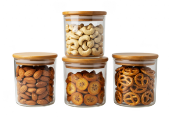 Four glass jars with wooden lids containing almonds cashews pretzels and dried fruit slices stacked on transparent background