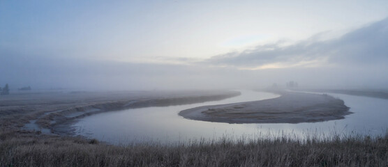 River bend disappearing into foggy horizon, soft gradient light and faded detail.
