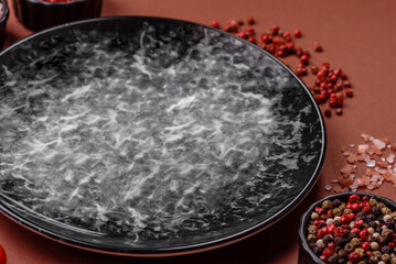 Empty round black plate for food, kitchen utensils on dining table. Empty plate