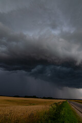 WEATHER Vertical Picture Dramatic black rain clouds over fields and country road