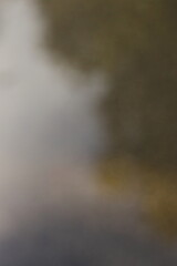 puddle reflection, wet asphalt, rainy day, nature reflection, tree silhouette, moody atmosphere, urban texture, abstract background, water surface, outdoor scenery, calm, dark tones, reflective mood