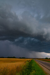 WEATHER Vertical Picture Dramatic black rain clouds over fields and country road