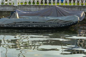 A covered boat at the pier longing for the sun and the thrill of adventure on the water. Boat sheltered on the pier waiting for the perfect weather to sail.