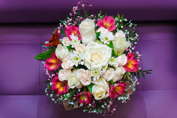 Delicate red alstroemeria and white roses flowers bordered with gypsophila arranged on purple background. Minimalist floral composition for summer, wedding or greeting designs.