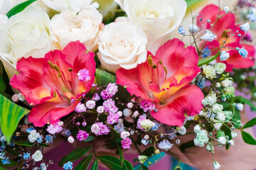 Flower arrangement background. Mixed bouquet of various types of flowers and colors. Red alstroemeria and white roses bordered with gypsophila.
