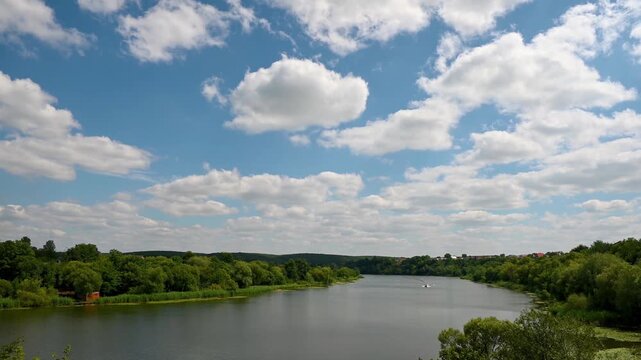 clouds over the river, a boat is sailing along the river