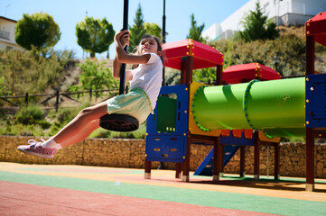 Happy Child Swinging in Vibrant Playground During Summer
