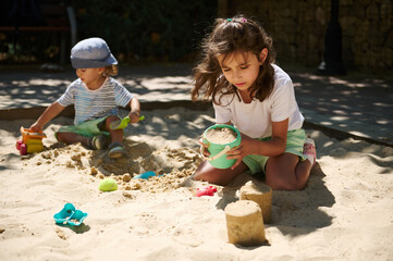 Children Playing in a Sunny Sandpit with Toys on a Summer Day
