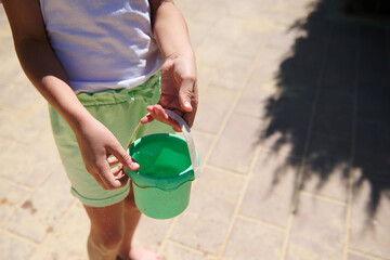 Close-Up of a Child Holding a Green Plastic Bucket Outdoors