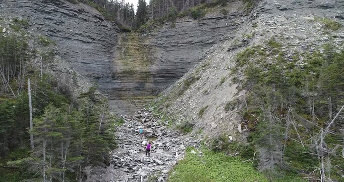 Two Women Climbing a Sedimentary Rock Formation in a Stratified Cliff at Anse de l'Indien in Anticosti Island, Quebec, Canada