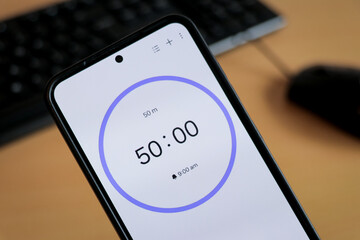 Phone white 50-minute timer to study with pomodoro method on laptop keyboard, study business background
