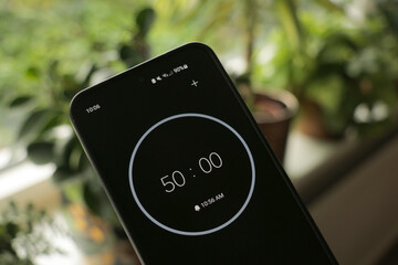 Phone with a black and white 50-minute timer to study or be productive, on a green, blurry plants background