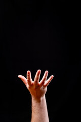 Fototapeta premium Hand Reaching Upwards on a Solid Black Background