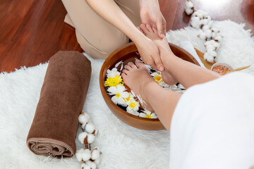 Woman indulges in blissful foot massage at luxurious spa salon while masseur give reflexology therapy in gentle day light ambiance resort or hotel foot spa. Quiescent
