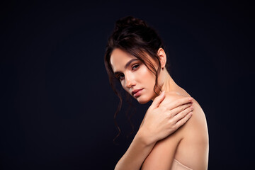 Fototapeta premium Portrait of a Young Brunette Woman with Bare Shoulders on a Dark Background, Showcasing Elegance