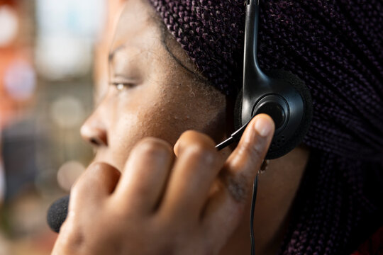 Call center employee wearing headset resolving customer concerns, speaking into microphone. Close up shot of customer service professional using headphones mic processing clients orders