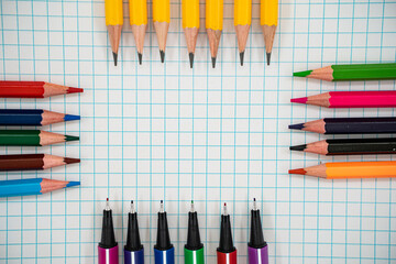 Back to school flat lay with colorful pencils and pens on graph paper with copy space.
