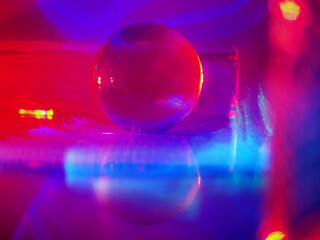 A clear glass ball is sitting on a pedestal. Colorful background. Abstract graphic background. Light effect. Planet in a space mood and feel.