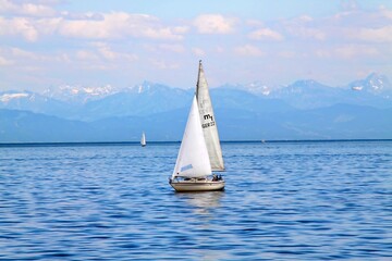 Naklejka premium Serene Sailboat on Calm Waters with Mountain Backdrop