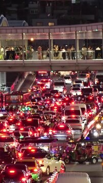 BANGKOK, THAILAND - AUGUST 2024 : High angle view of busy traffic around downtown shopping area at night. Transportation and street traffic concept video.