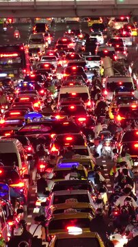 BANGKOK, THAILAND - AUGUST 2024 : High angle view of busy traffic around downtown shopping area at night. Transportation and street traffic concept video.