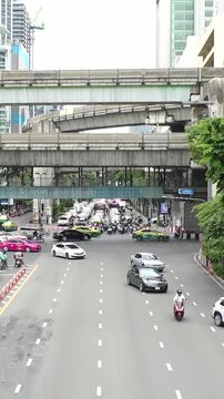 BANGKOK, THAILAND - AUGUST 2024 : View of street traffic at busy crossing. Many cars, motorbikes, tuk tuk and taxi on the road. Transportation concept video. Time lapse shot in daytime.