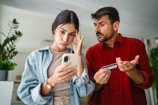 Young couple arguing about online shopping and credit card expenses at home - Powered by Adobe