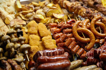 Assorted grilled meats and vegetables on skewers, including sausages, mushrooms, and potatoes, arranged beautifully on a platter, showcasing a vibrant culinary display