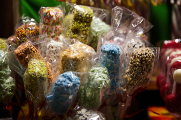 Colorful candy pops wrapped in clear plastic, showcasing vibrant sprinkles and textures, arranged in a festive display, enticing viewers with sweet treats and joyful atmosphere