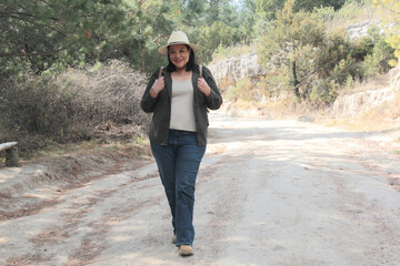 A 40-year-old Latina woman hikes in the mountains to fully enjoy nature and sunlight, experiencing well-being and empowerment