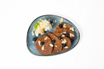 Homemade pancakes with blueberries and almond flakes, served with cottage cheese and honey on a plate. Isolated on white background