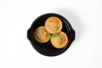 Homemade banana muffins with fresh banana slices and mint leaves, served on a plate. Isolated on white background