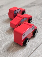 Obraz premium Red wooden toy cars on a light wooden floor.