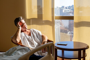 Exhausted patient resting in sunlit hospital room