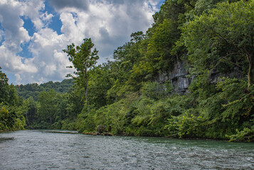 river in the forest of the ozarks with limestone bluff