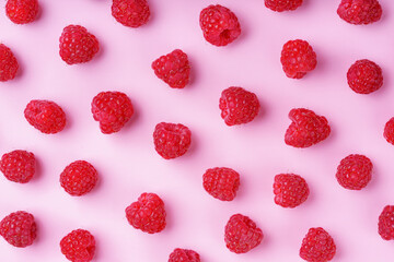 Scattered ripe red raspberries on pastel pink background. Flat lay, top view. Colorful minimal food composition, food design. Perfect for healthy eating and summer fruit, harvest concepts.